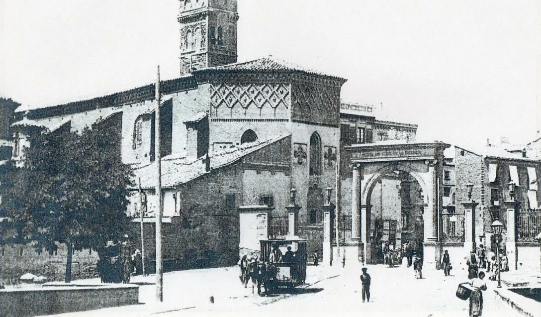 Vista de la Puerta del Duque desde el sur, con la iglesia de San Miguel y un tranvía de mulas